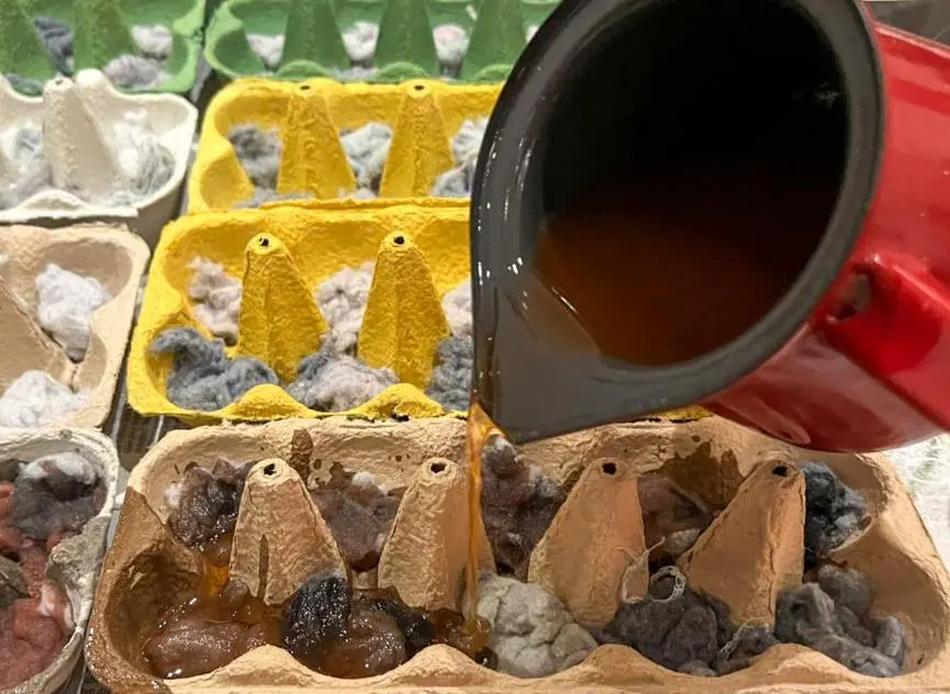 Pouring paraffin into egg cartons filled with lint