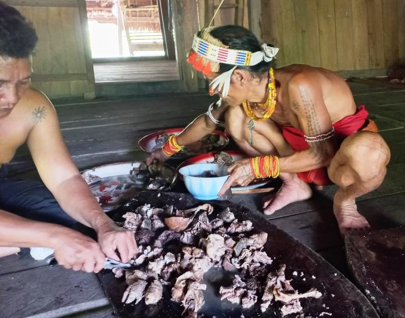 Mentawai dividing meat of domestic pigs