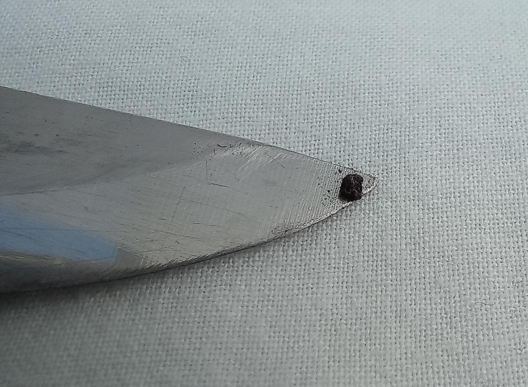 Chunky grain of potassium permanganate on a knife tip