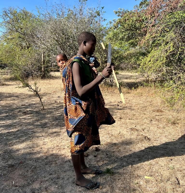 Hadza women preparing a wooden digging stick