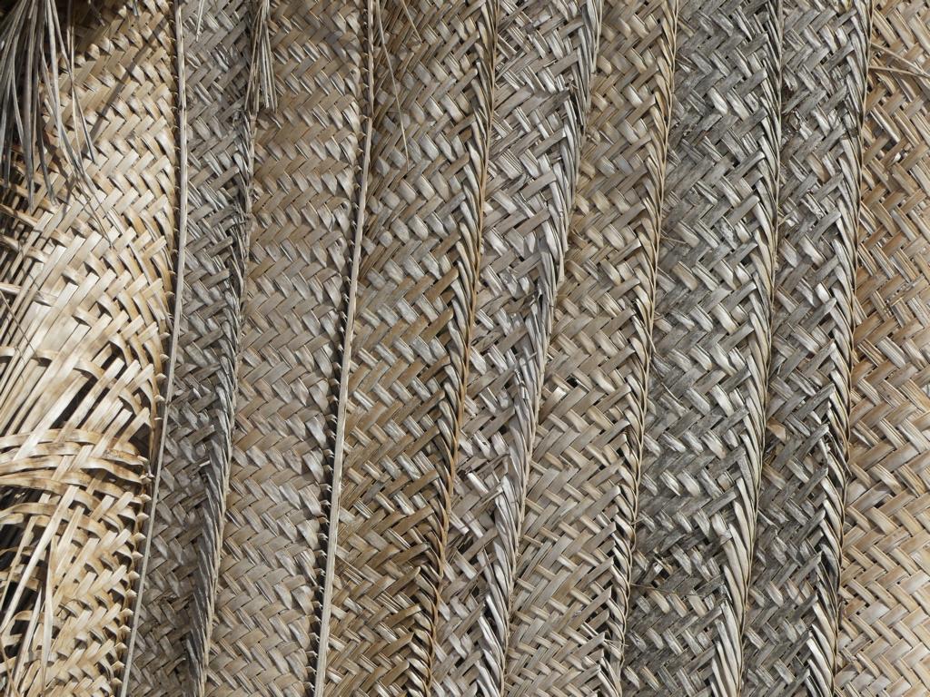 Vertically stacked woven coconut panels serve as sidewalls for beach huts.