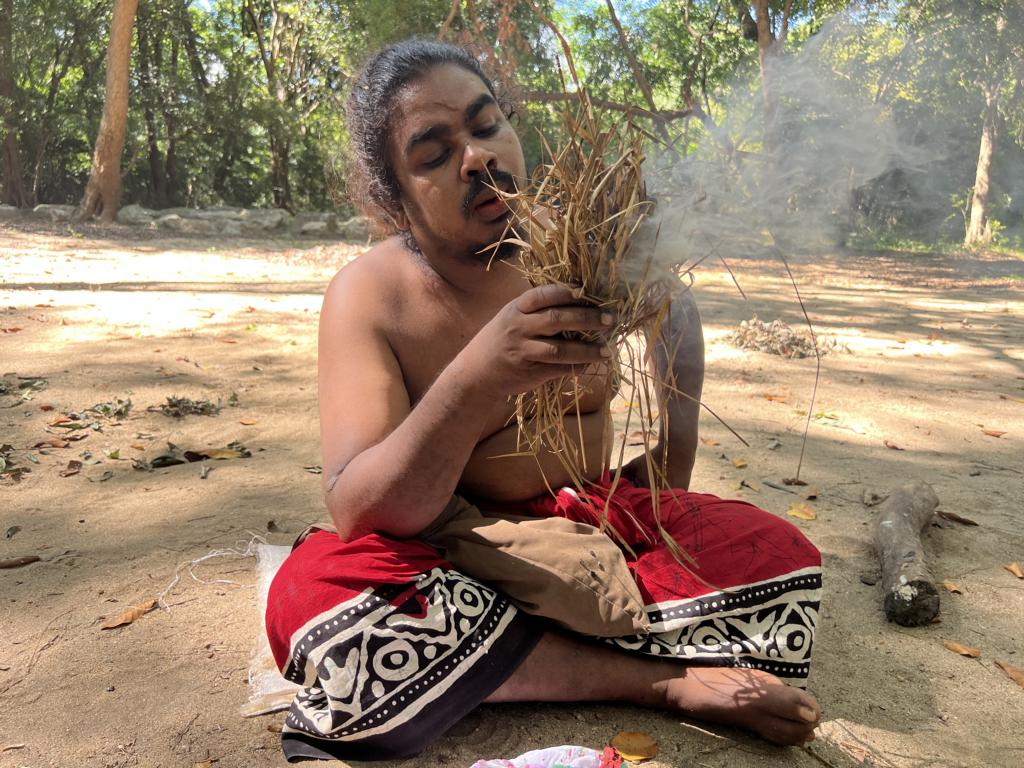 Burning cotton roll in a tinder grass bundle